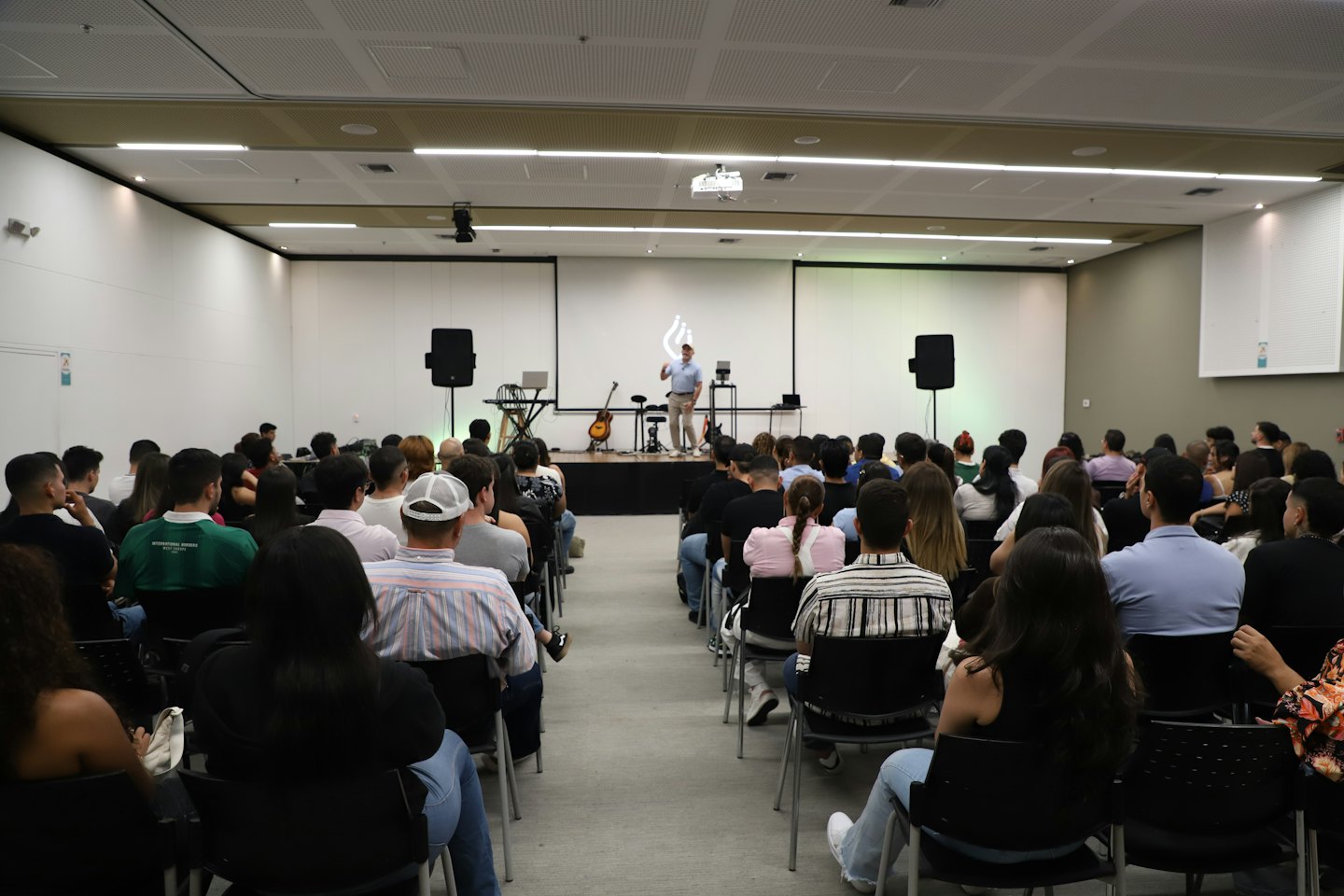 Un conférencier s'adresse à un public attentif dans un auditorium moderne.