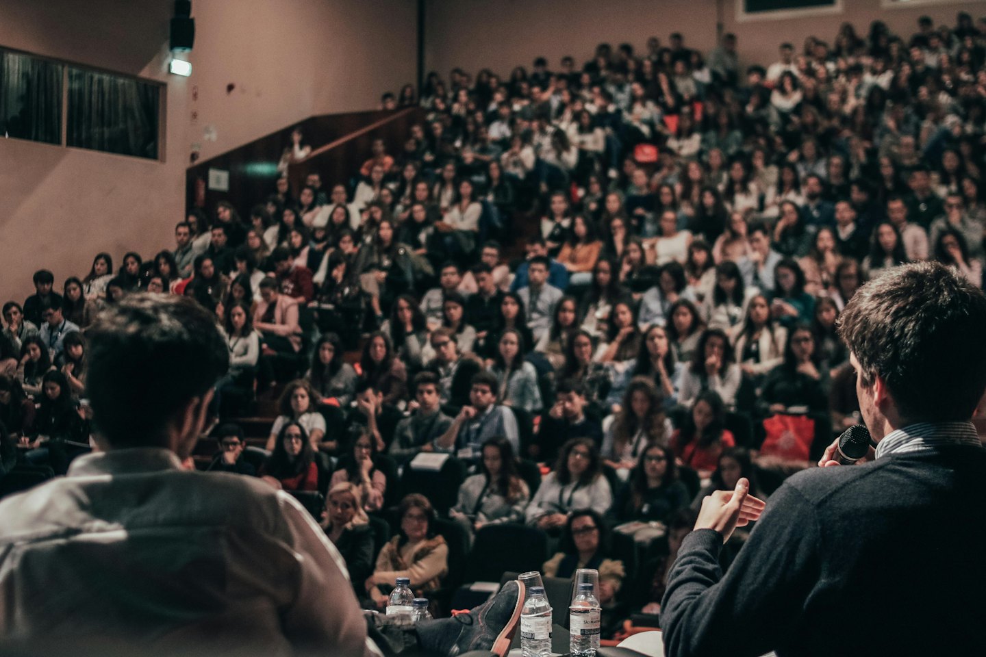 Des intervenants sur scène présentant à un large public dans un auditorium.